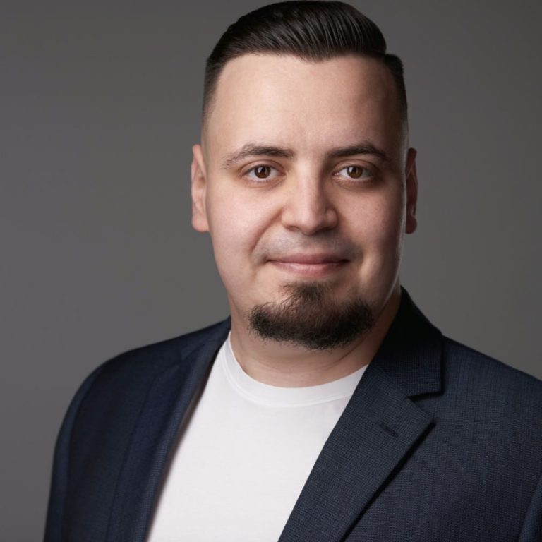 Sipos Zoltán portréja, sötét zakóban, szürke háttér előtt